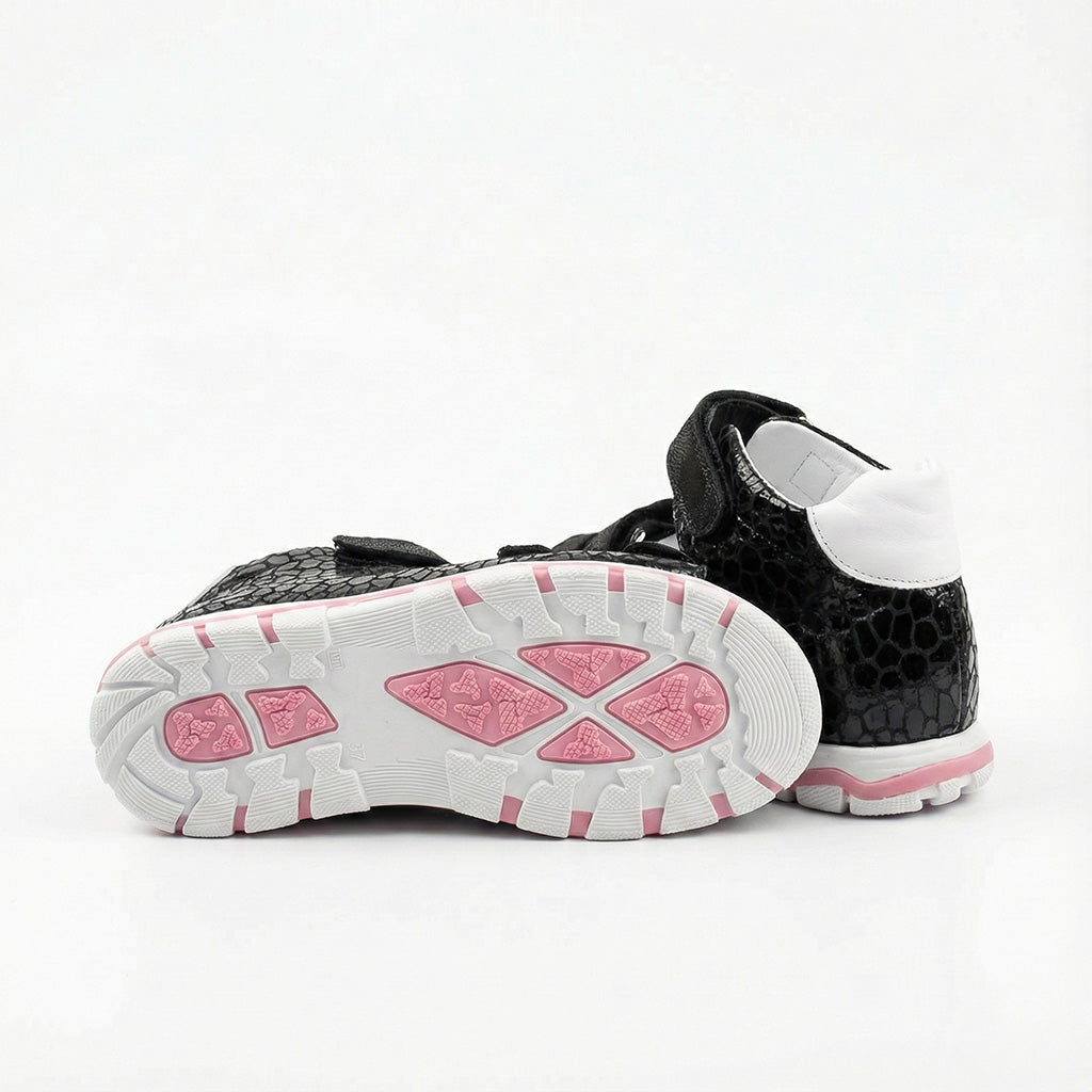 Children’s black orthopedic sandals with reptile-textured finish, white lining, and pink-accented sole.