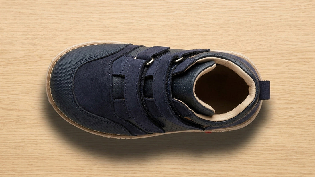 Top-down landscape view of a navy blue children's orthopaedic shoe showing the wide, asymmetrical toe box designed for natural toe splay and vertical clearance.