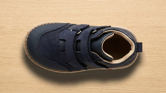 Top-down landscape view of a navy blue children's orthopaedic shoe showing the wide, asymmetrical toe box designed for natural toe splay and vertical clearance.