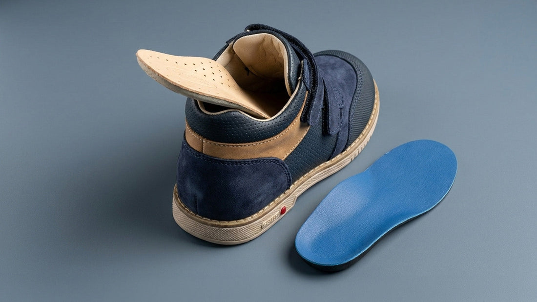 Studio product view of a navy blue children's orthopaedic shoe showing the deep internal cavity and a removable insole lifted to demonstrate space for custom orthotic accommodation.