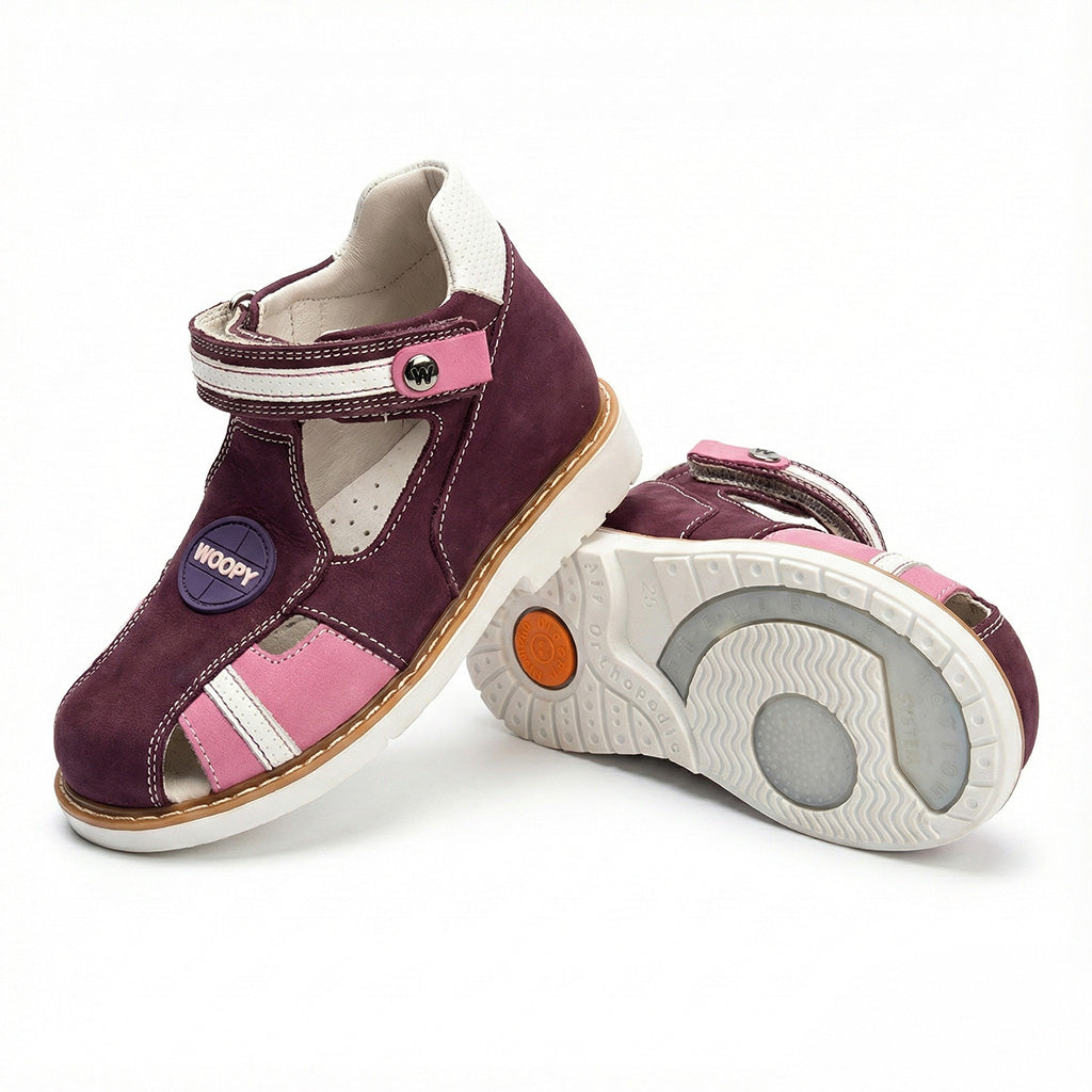 Children’s orthopedic sandals in purple with pink and white accents, Velcro strap, ‘WOOPY’ branding, and supportive sole.