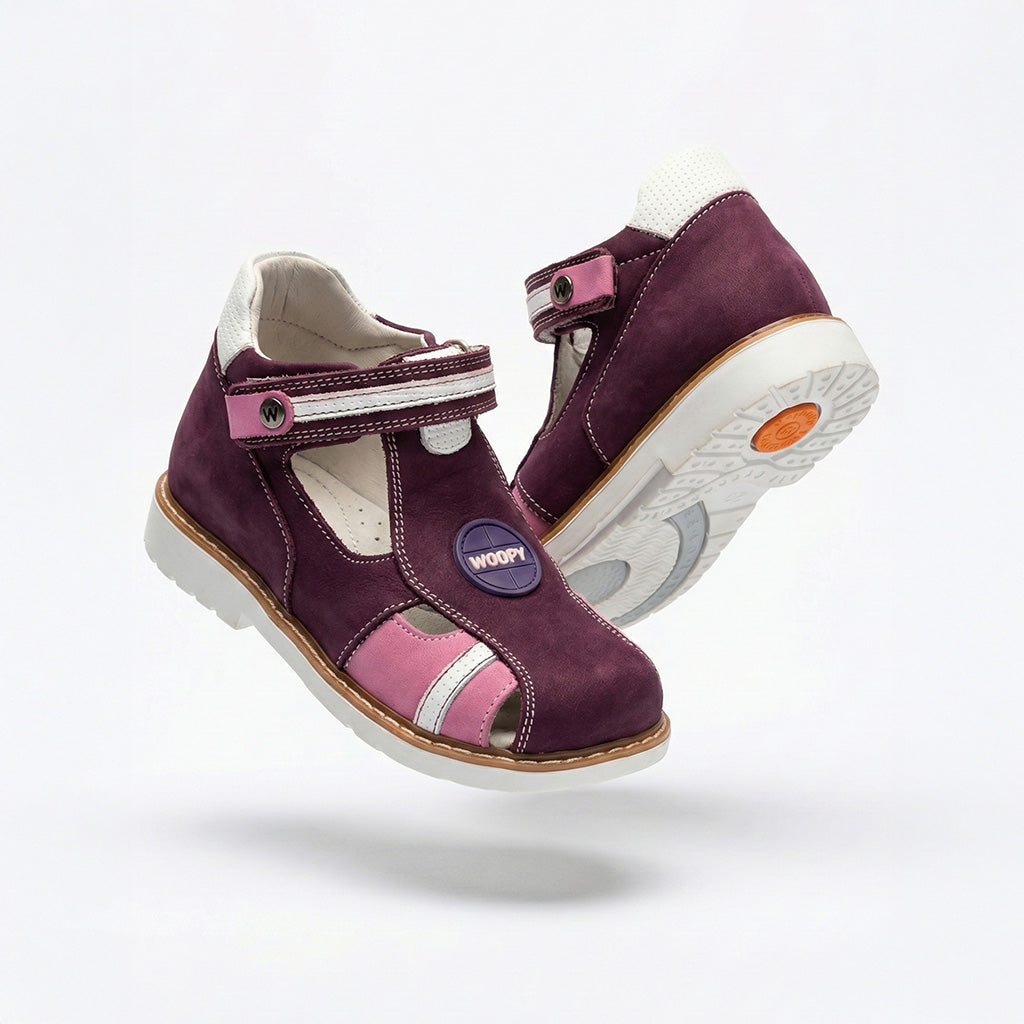 Girls’ orthopedic shoes in dark purple with cutout sides, Velcro fastening, arch support, and Thomas heels, featuring ‘WOOPY’ logo patch.