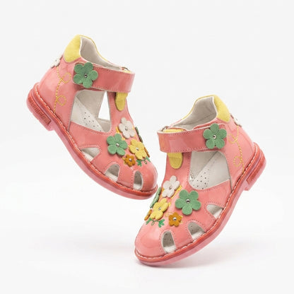 Children’s pink closed‑toe orthopedic sandals with Velcro straps, flower accents, arch and ankle support, featuring Thomas heels by Minimen.
