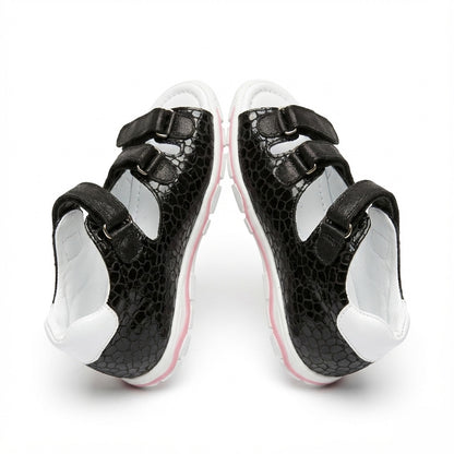 Girls’ orthopedic sandals in black with Velcro closure, arch and ankle support, and pink sole accent.