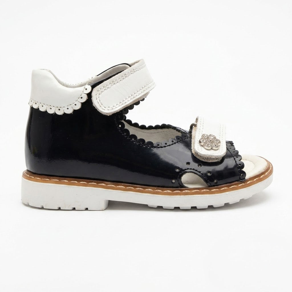 Side view of girls navy leather open-toe sandals showing built-in arch support, sturdy Thomas heel, and white sole.