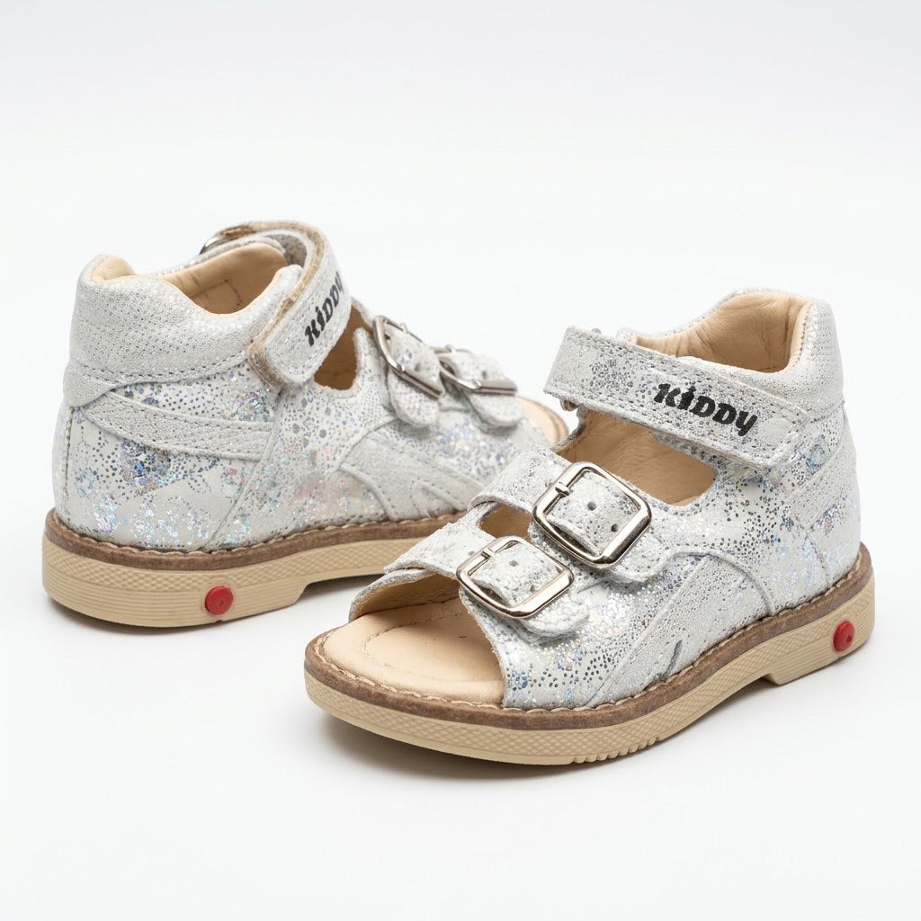 Shimmering silver leather mid-top kids sandals with two buckle straps, top Velcro strap, and sturdy beige sole.