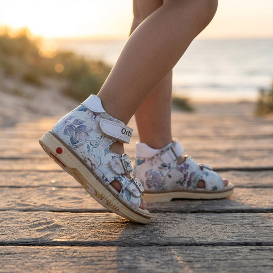 Kids orthopaedic sandals in floral white leather with three adjustable buckle straps and a supportive cream sole.