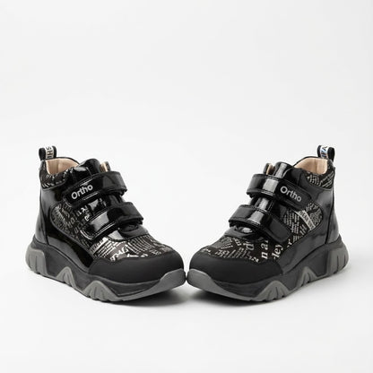 Supportive orthopedic sneakers for kids with dual Velcro closure, printed upper, rugged sole, and Ortho branding.