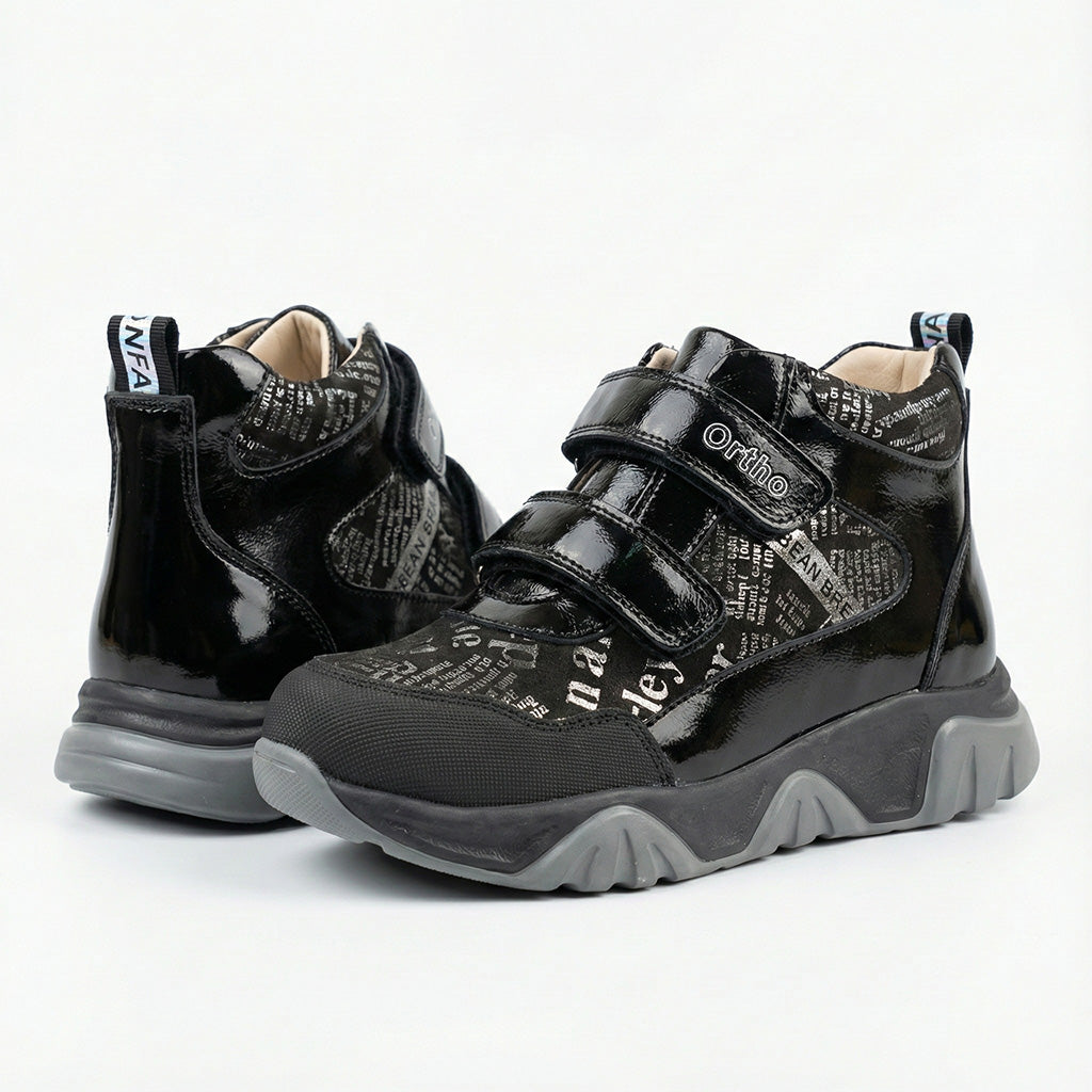 Children’s orthopedic shoes in black with Velcro straps, printed design, arch support, and Thomas heels by Ortho Shoes.