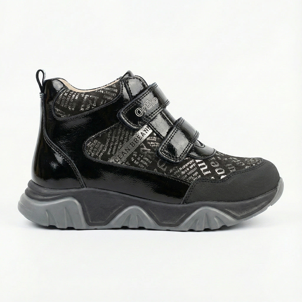 Supportive children’s orthopedic shoe in black with dual Velcro closure, printed upper, and rugged sole.