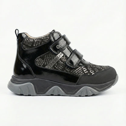 Supportive children’s orthopedic shoe in black with dual Velcro closure, printed upper, and rugged sole.
