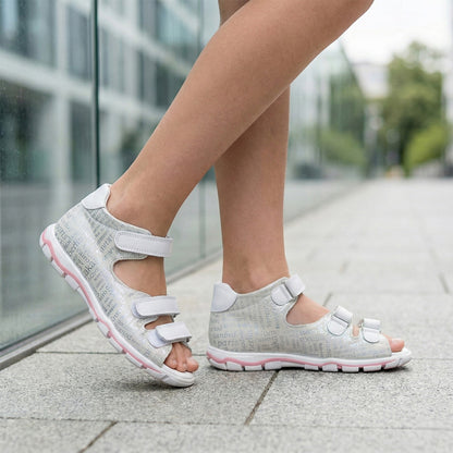 Girls’ orthopedic sandals in white with Velcro straps, city-name print, pink sole accent  by Ortho Shoes.