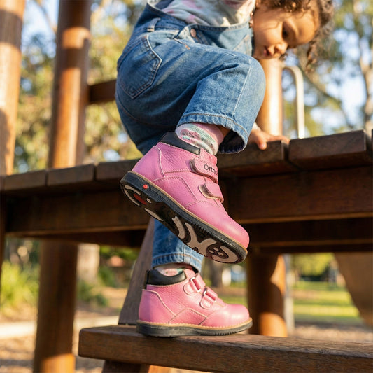 Girls’ orthopedic boots in pink with Velcro closure, arch and ankle support, Thomas heels, and black sole by Ortho Shoes.
