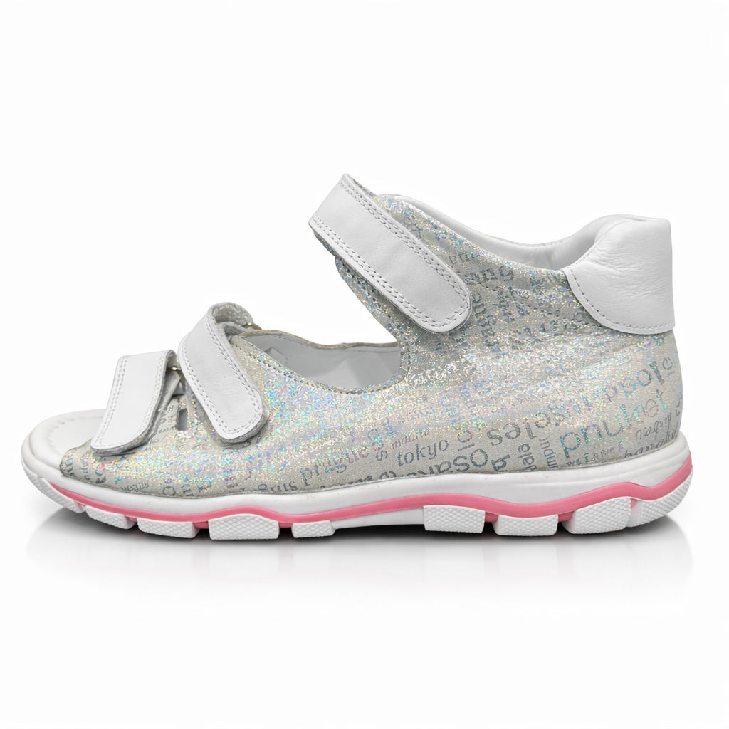 Girls’ orthopedic sandals in silver with white Velcro straps, arch and ankle support, and city-name print by Ortho Shoes.