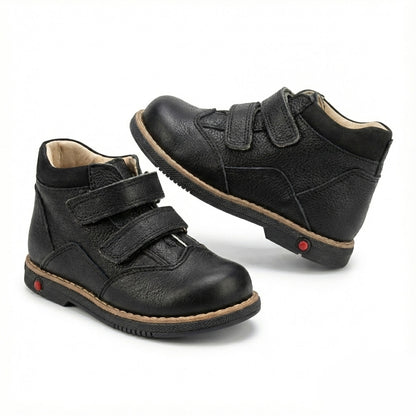 Supportive black orthopedic half-boots for kids with Velcro closure, arch and ankle support, Thomas heels, rugged sole, and dust-resistant design by Ortho Shoes.