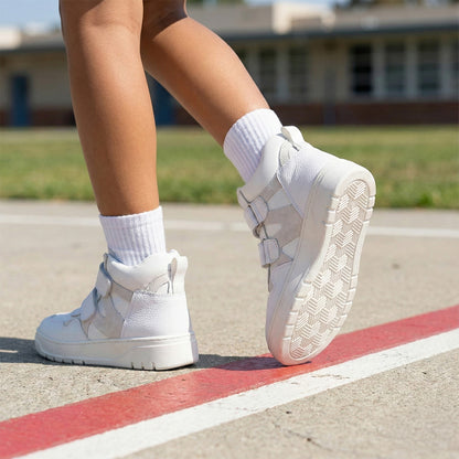 Children’s white orthopedic high-top sneakers with Velcro straps, ankle support, and non-slip sole for school wear by Ortho Shoes.