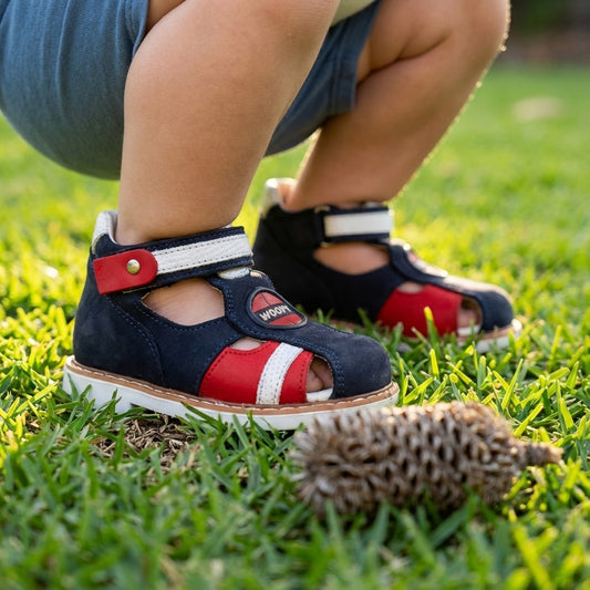 Kids’ orthopedic sandals in blue, red, and white with Velcro closure, closed toe, arch and ankle support, and WOOPY branding.